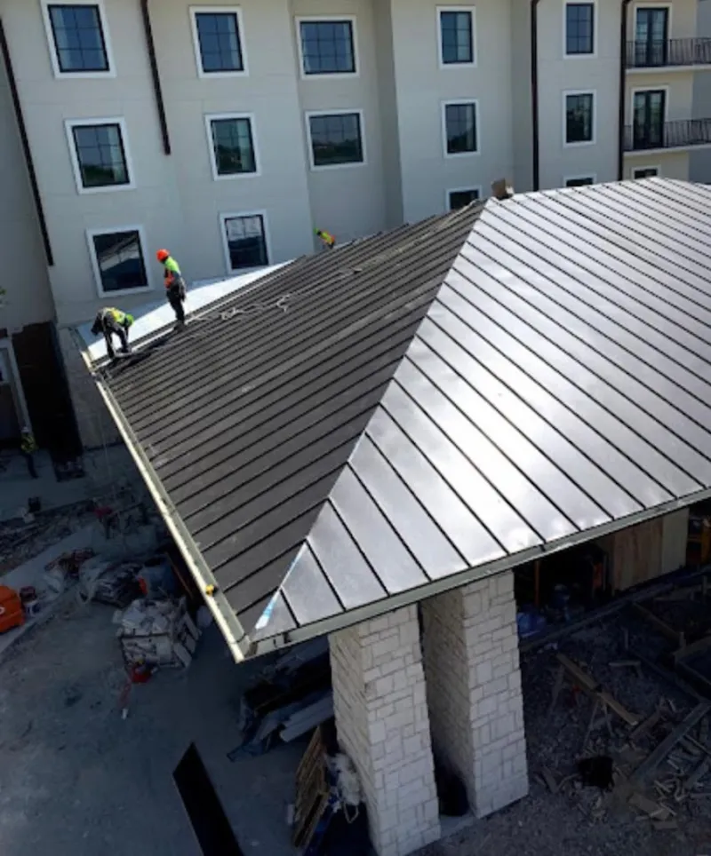 Crew installing standing seam metal roof panels on a commercial project in Romulus